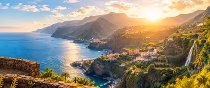 Panoramic view of Madeira's rugged coastline at golden sunset, with lush green cliffs, terracotta-roofed village, and Atlantic Ocean